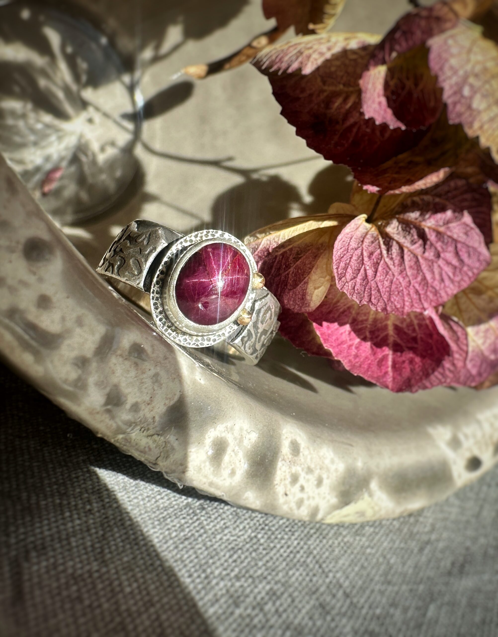 Floral gestalteter Ring mit einem Sternrubin und Gold-Details